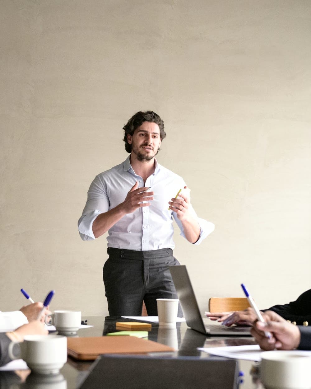 A man standing to give his pitch at a breakfast meeting, seated members listening over coffee in the foreground.